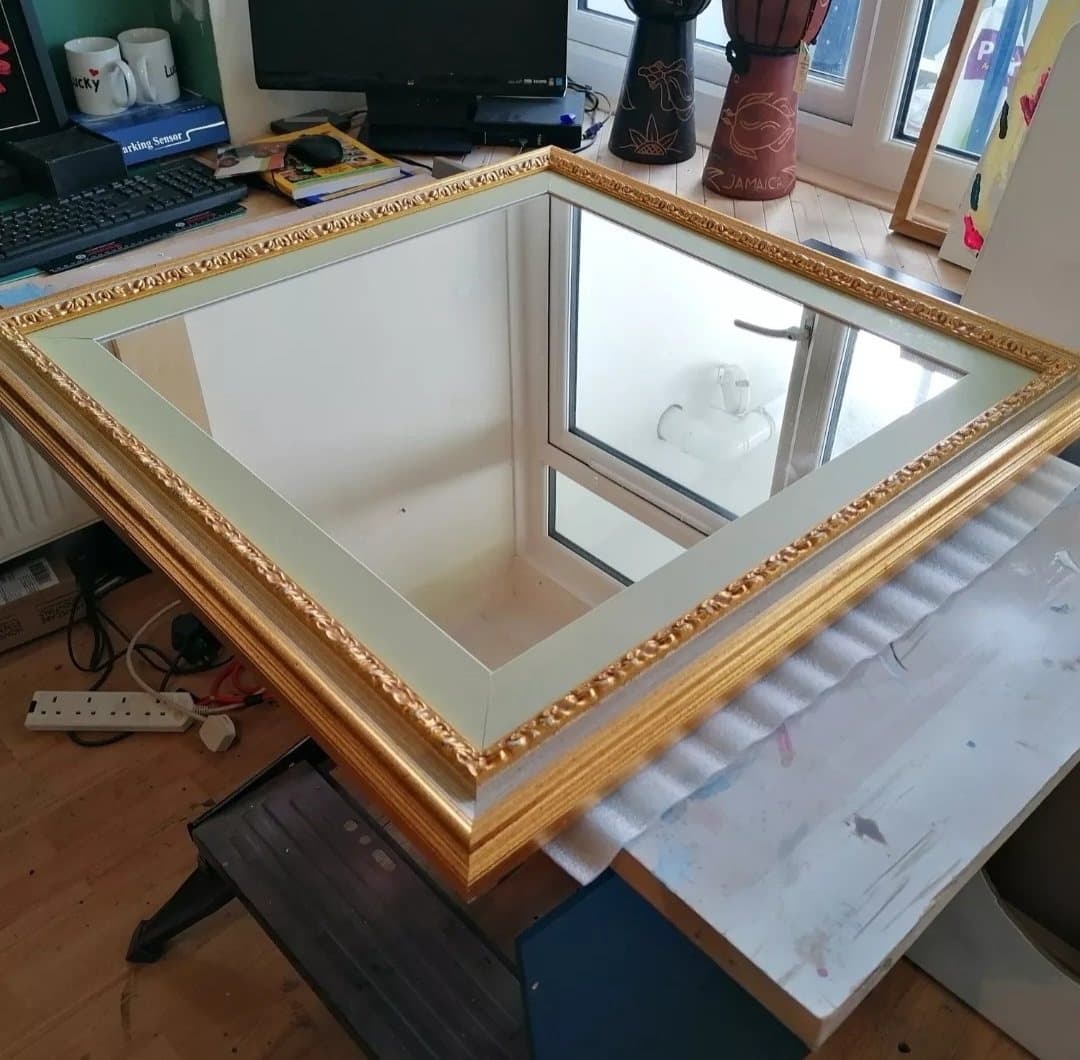 Ornate gilded mirror frame with a pale green card mount, on the workshop bench