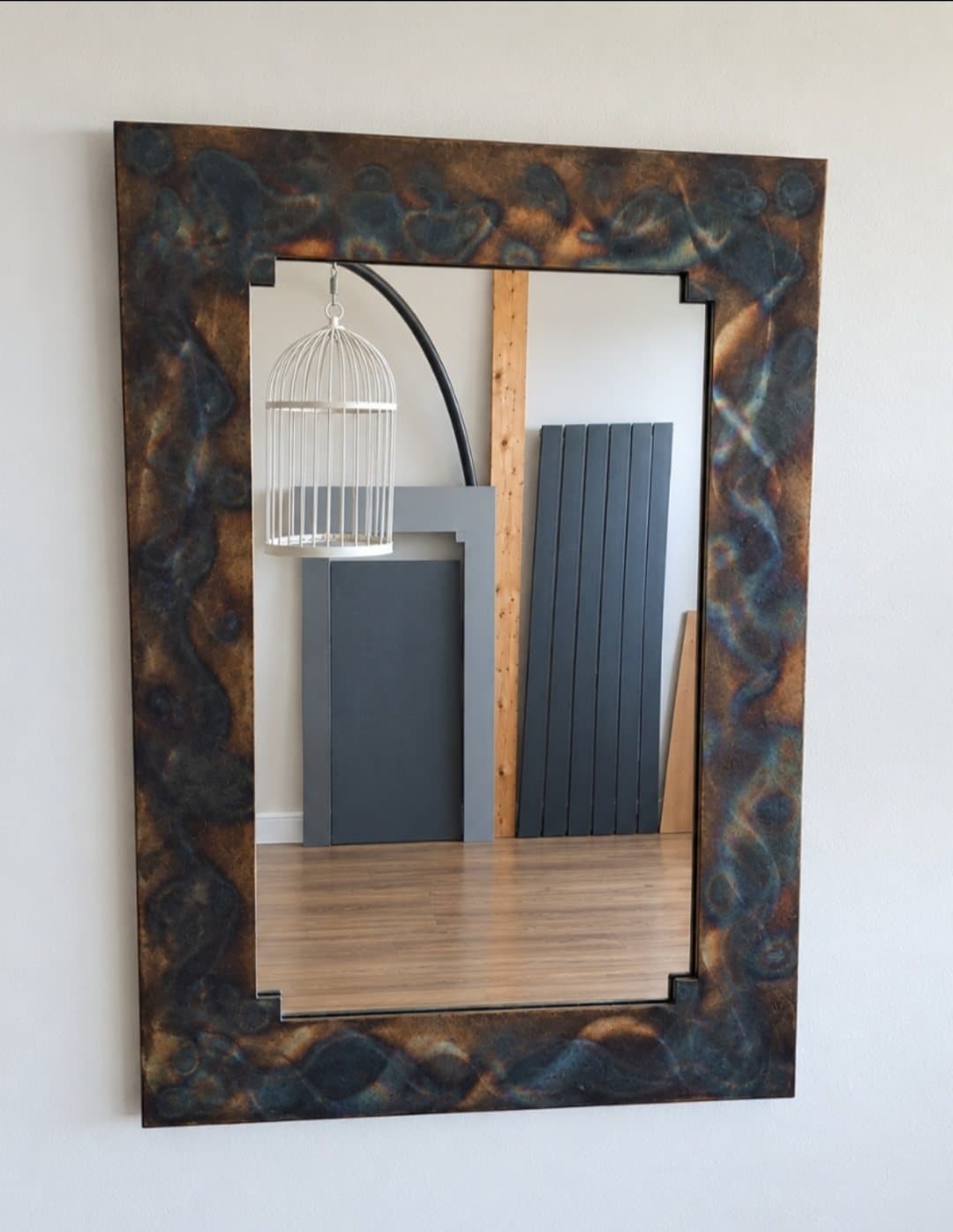 Rectangular mirror with a wide frame in a mottled blue, bronze and black finish