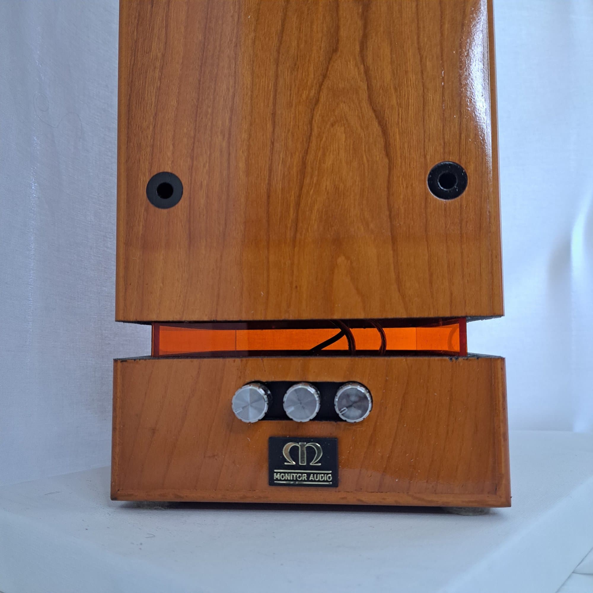 Detail of the tower speaker base with its orange glow and three chrome controls